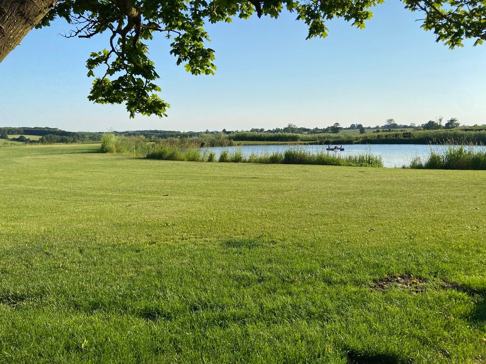 A lake with grass and a tree in the foreground at The Cart Shed in Bedford