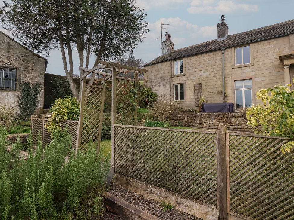 A garden scene with a tree and fence at Wood End Farm Cottage