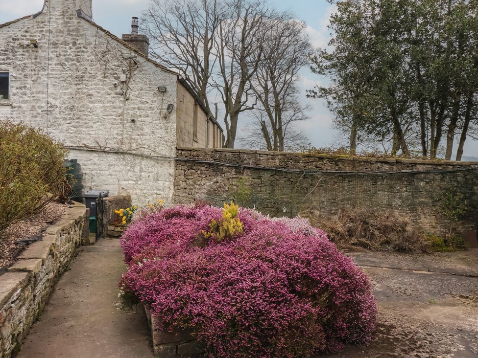 A garden with a bush and path beside a stone wall at Wood End Farm Cottage