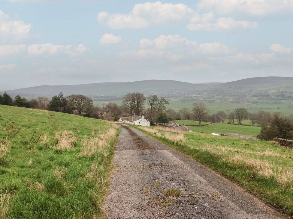 A road leading to a house with hills in the background at Wood End Farm Cottage