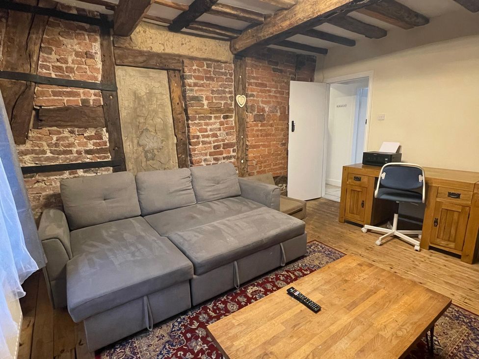 A living room with a sofa, table, and chair at 15A Currier Lane Ashton-under-Lyne