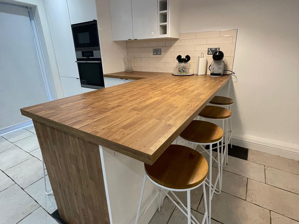 A kitchen with a wooden counter and stools at 15A Currier Lane Ashton-under-Lyne