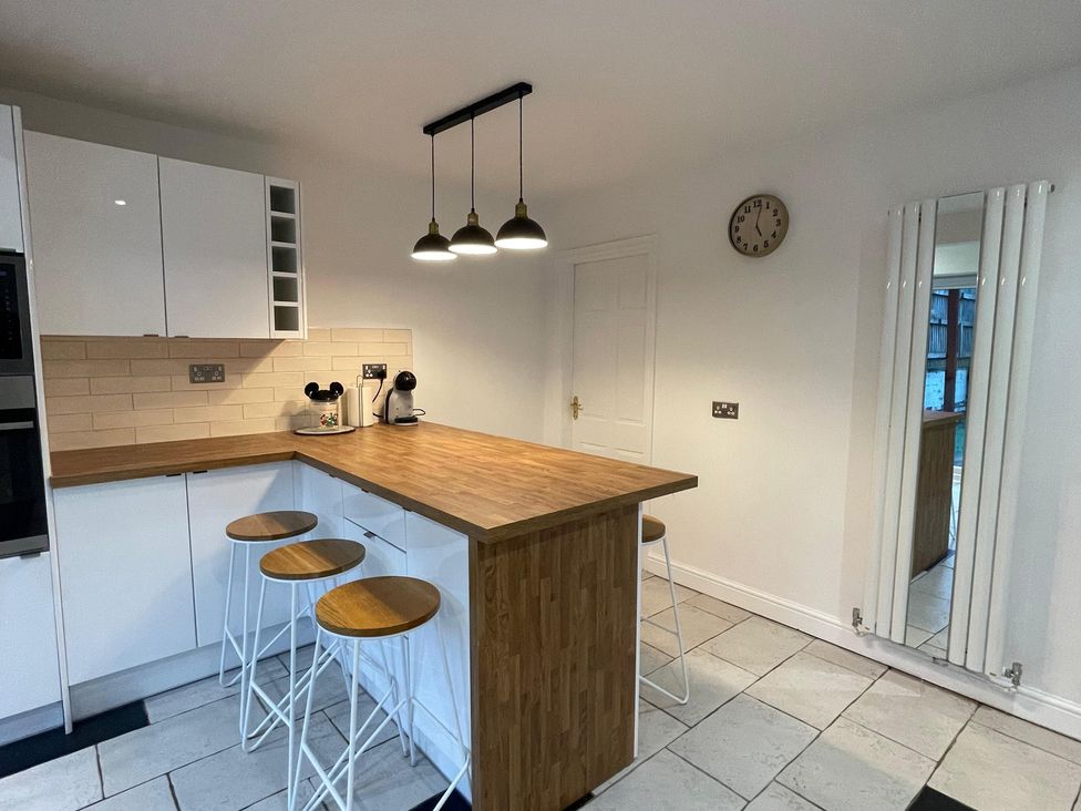 A kitchen with a wooden island and stools at 15A Currier Lane Ashton-under-Lyne
