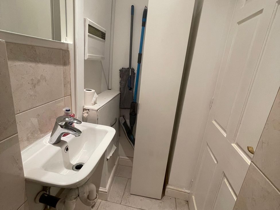 A bathroom with a sink and cleaning supplies at 15A Currier Lane Ashton-under-Lyne