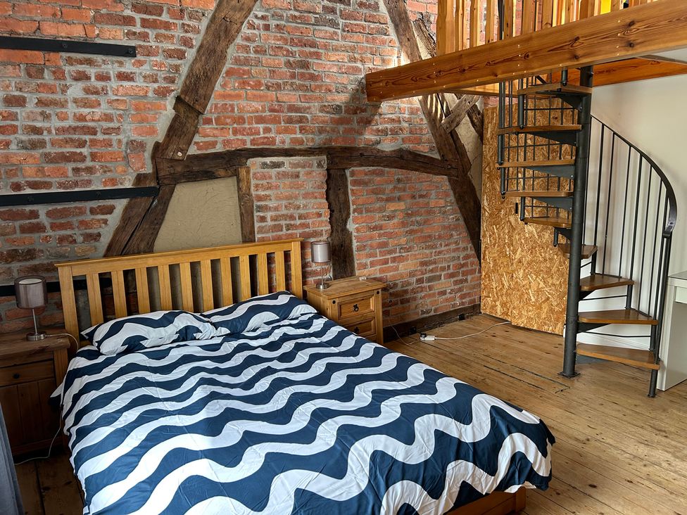 A bedroom with a bed and spiral staircase at 15A Currier Lane Ashton-under-Lyne