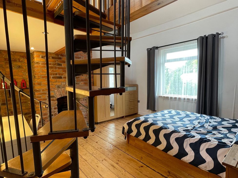 A bedroom with a spiral staircase and a bed at 15A Currier Lane Ashton-under-Lyne