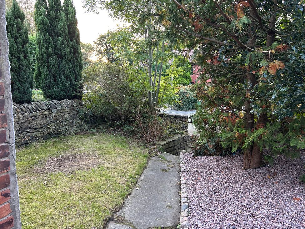 A garden with a stone wall and pathway at 15A Currier Lane Ashton-under-Lyne