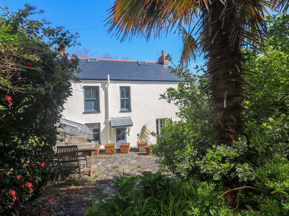 A garden with a dining table and palm tree at Pedn Brose Near Mousehole