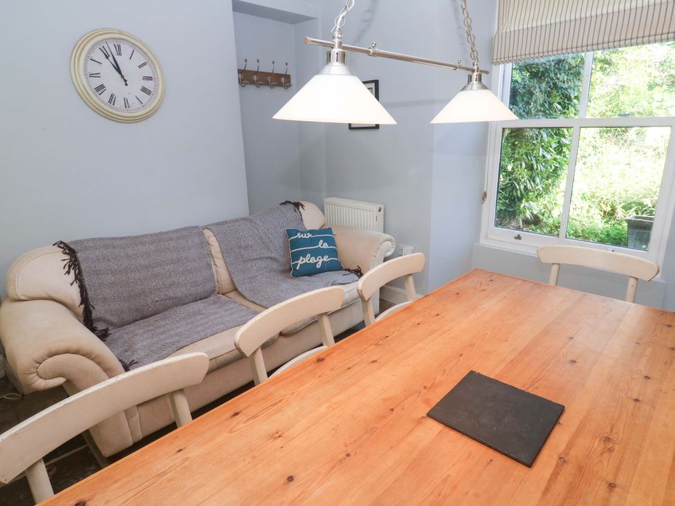 A dining room with a sofa and a wooden table at Pedn Brose near Mousehole
