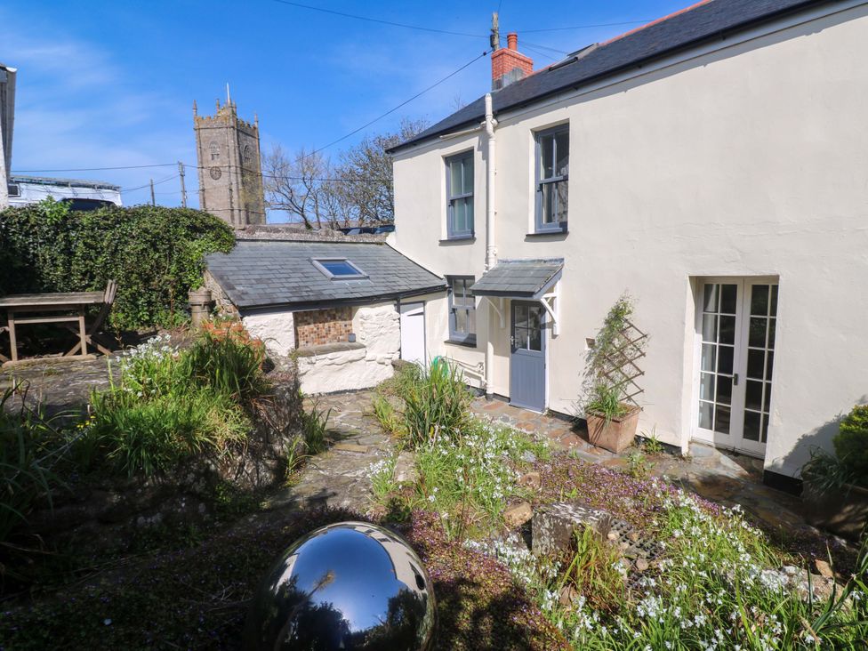 An outdoor garden with a house corner and view of a church tower at Pedn Brose near Mousehole