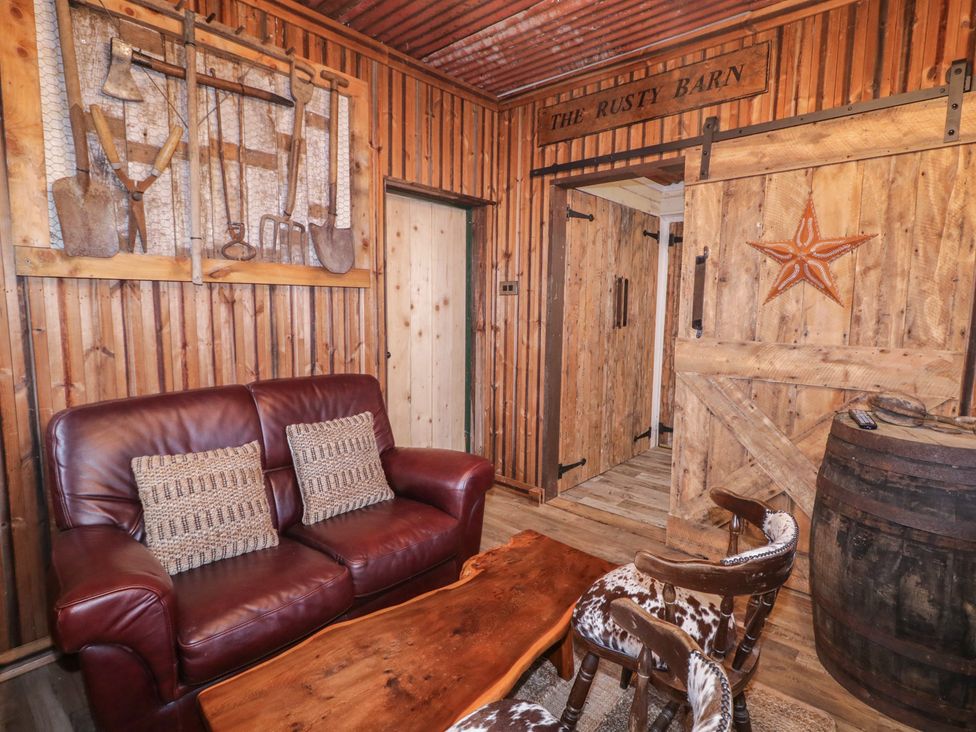 A living room with a sofa, wooden table and decorative wall art at The Rusty Barn in Limavady
