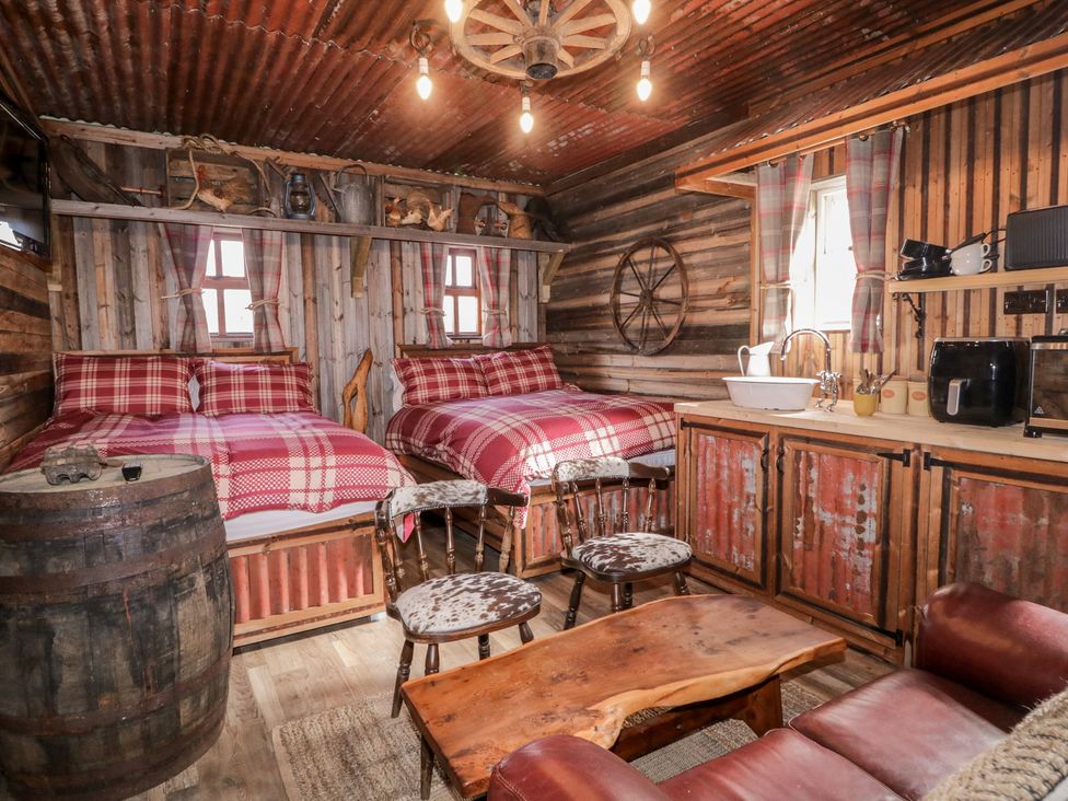 A bedroom with two beds and a wooden table at Rusty Barn in Limavady
