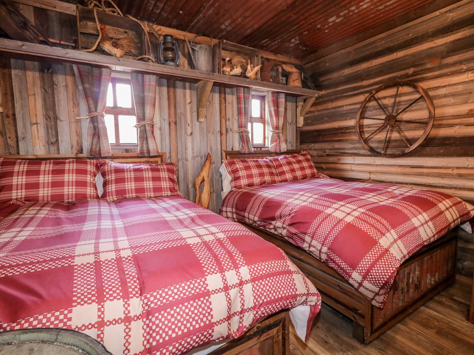 A bedroom with two beds and decorative wall elements at Rusty Barn in Limavady