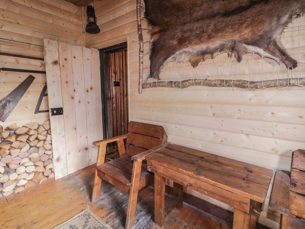 A snug with wooden furniture and logs at Rusty Barn in Limavady