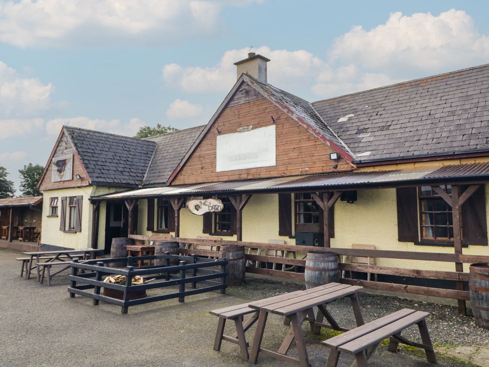 An outdoor seating area with tables and barrels at Rusty Barn in Limavady
