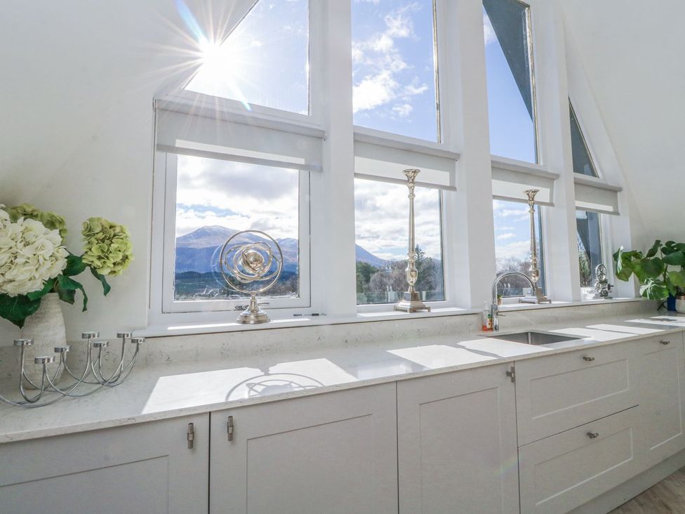 A kitchen with windows overlooking mountains at Macgregor Ranch in Achnabobane near Spean Bridge