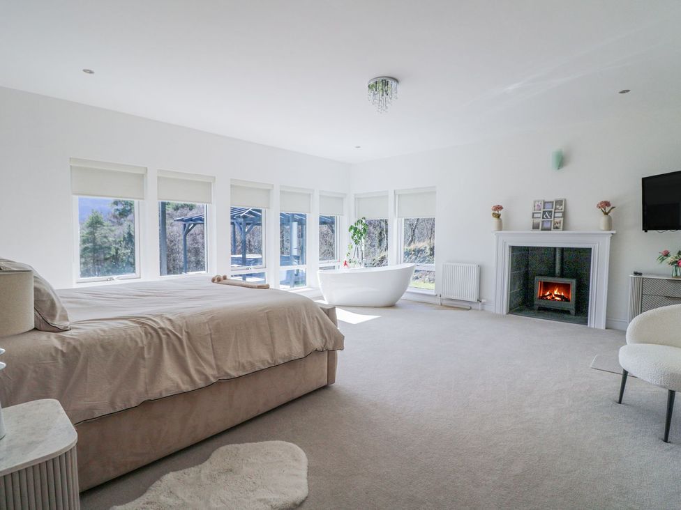 A bedroom with a bathtub and fireplace at Macgregor Ranch in Achnabobane near Spean Bridge