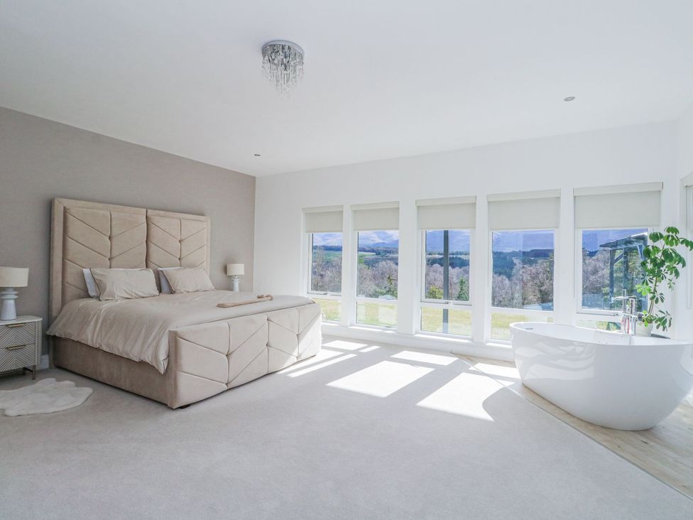 A bedroom with a bed and large windows at Macgregor Ranch near Achnabobane near Spean Bridge