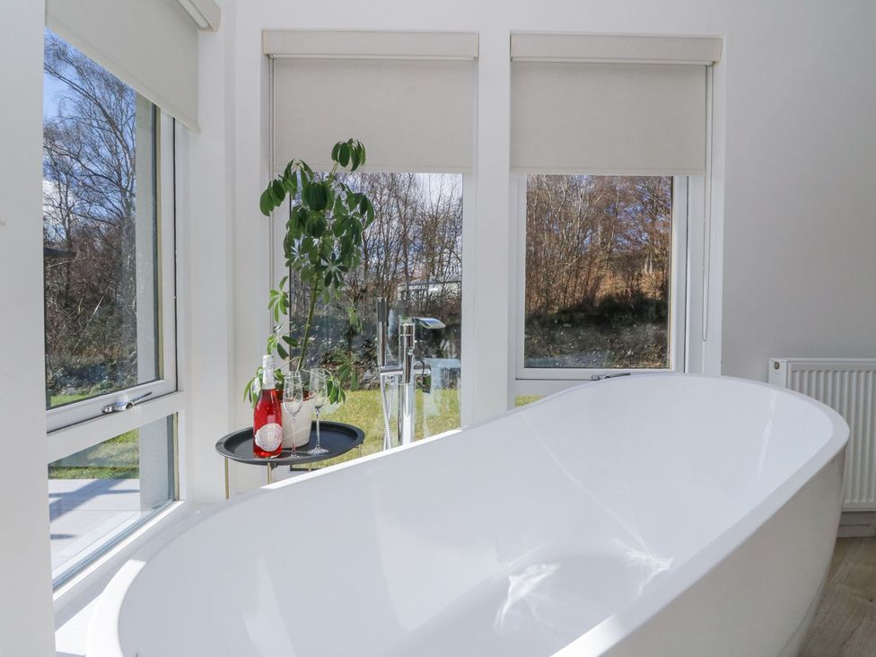 A bathroom with a bathtub and windows at Macgregor Ranch Achnabobane near Spean Bridge
