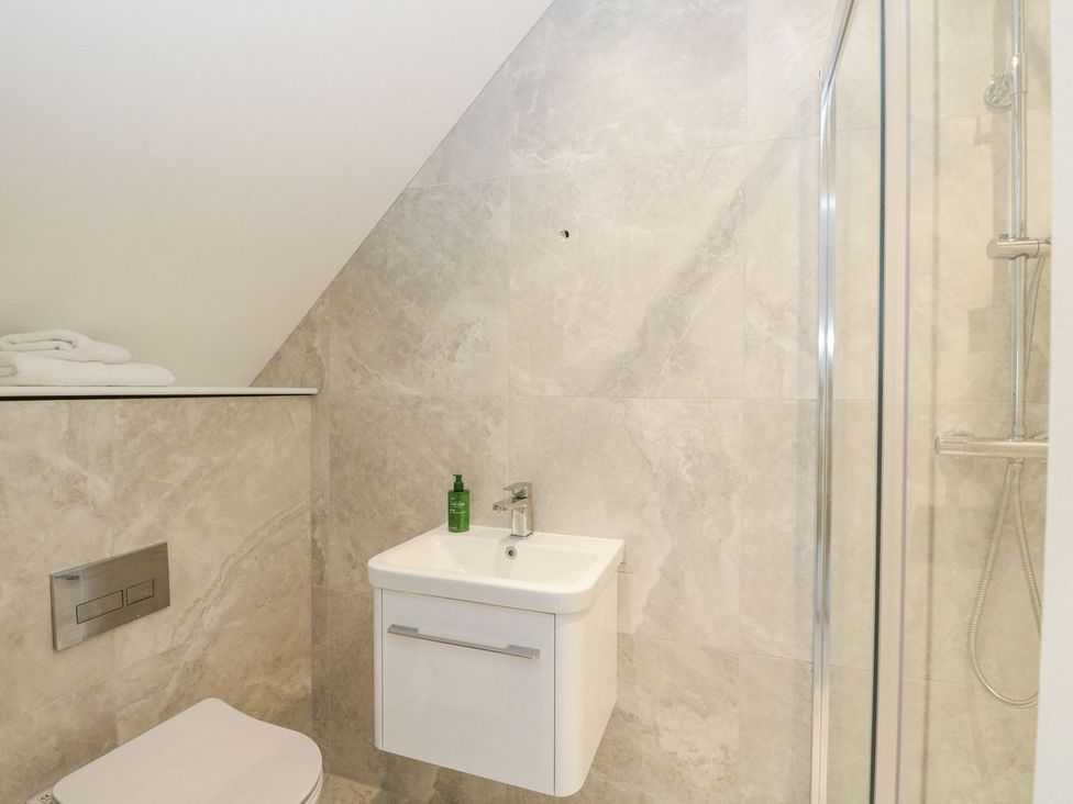 A bathroom with sink, toilet, towels and shower at Macgregor Ranch Achnabobane near Spean Bridge