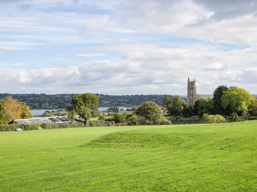 A view of a field with a church tower and trees at Redwood Cottage in Bristol