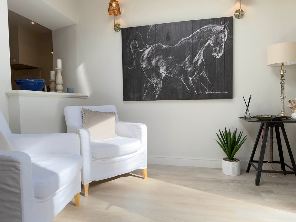 A living room with a horse painting and white chairs at Redwood Cottage in Blagdon