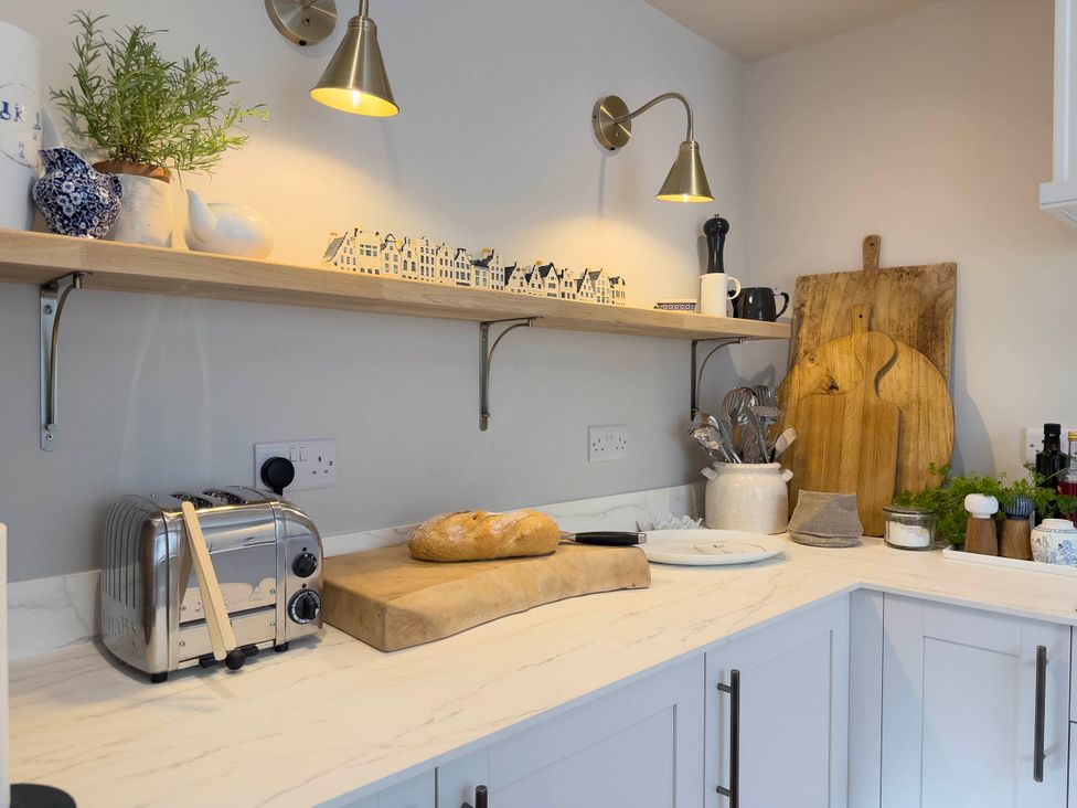 A kitchen countertop with a loaf of bread and utensils at Redwood Cottage in Blagdon