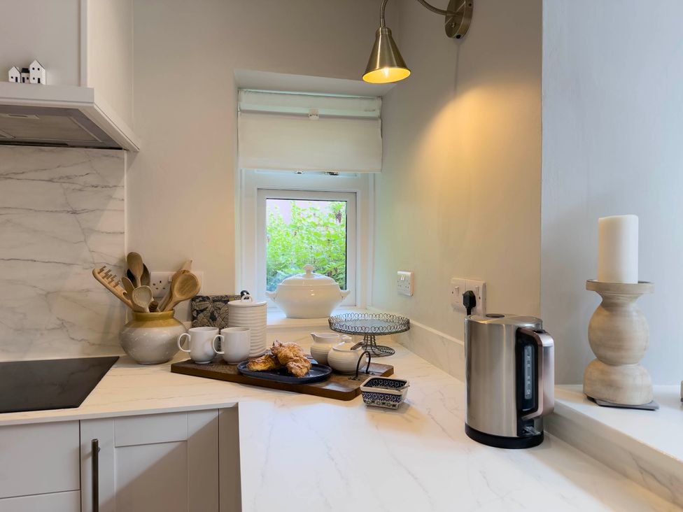 A kitchen with a kettle, teacups, and a cookie on a serving tray at Redwood Cottage in Blagdon