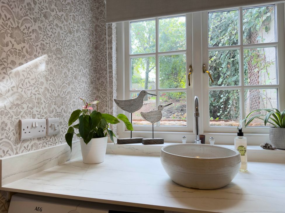 A bathroom sink with a plant and decorative figurines at Redwood Cottage in Blagdon