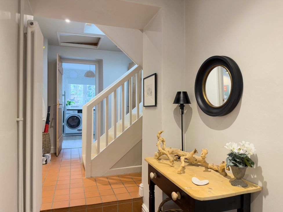 A hallway with a staircase and table at Redwood Cottage in Blagdon