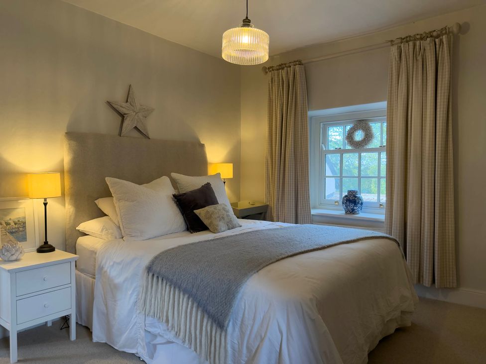 A bedroom with a bed, bedside tables, and a window at Redwood Cottage in Blagdon