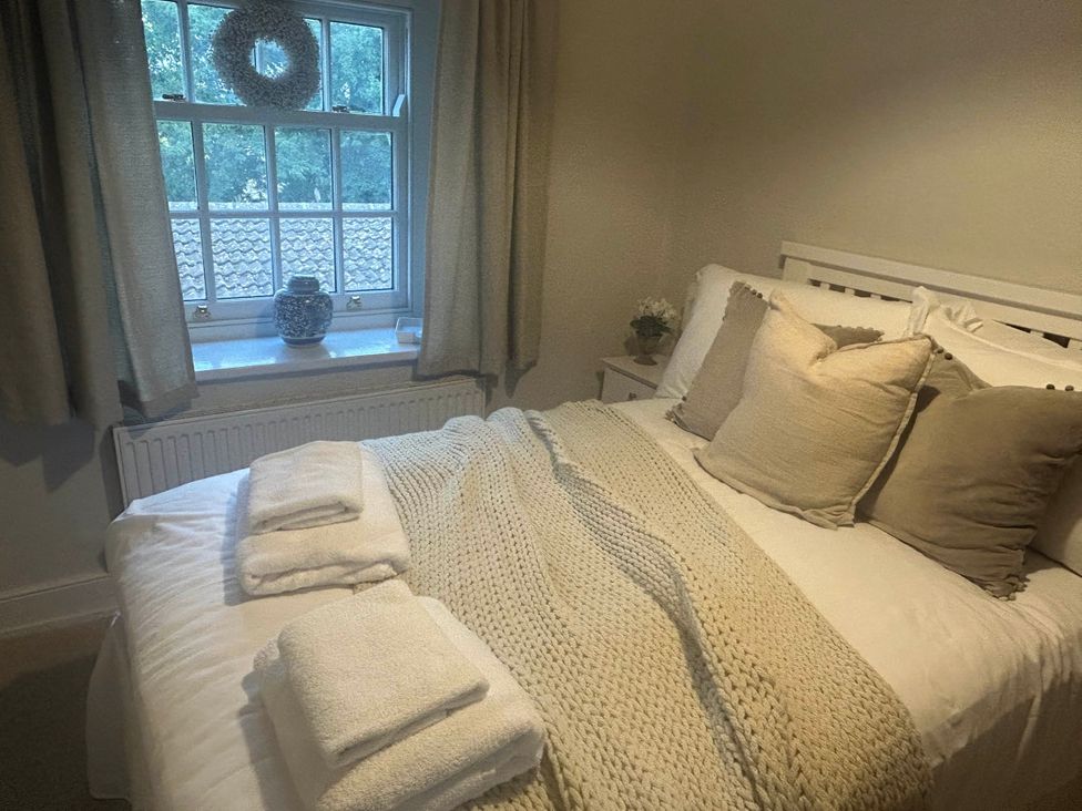 A bedroom with a bed, pillows, and a window at Redwood Cottage in Blagdon