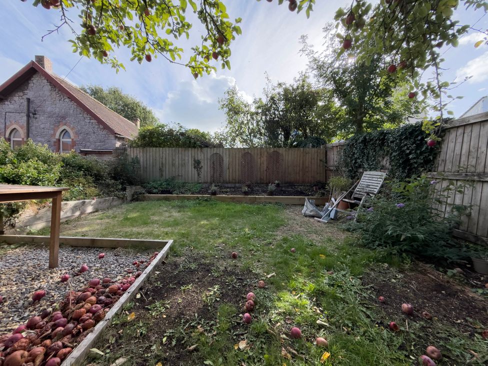 A garden with a table and apples on the ground at Redwood Cottage in Blagdon
