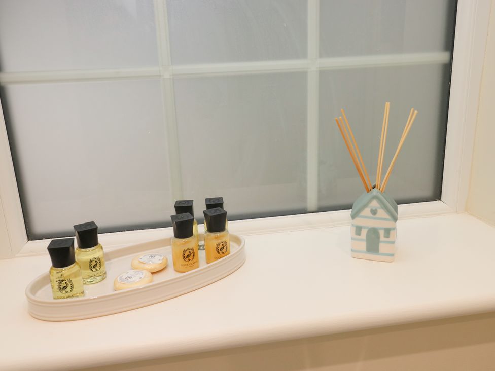 A bathroom windowsill with nail polish and a reed diffuser at Sea Folly in Porthcawl