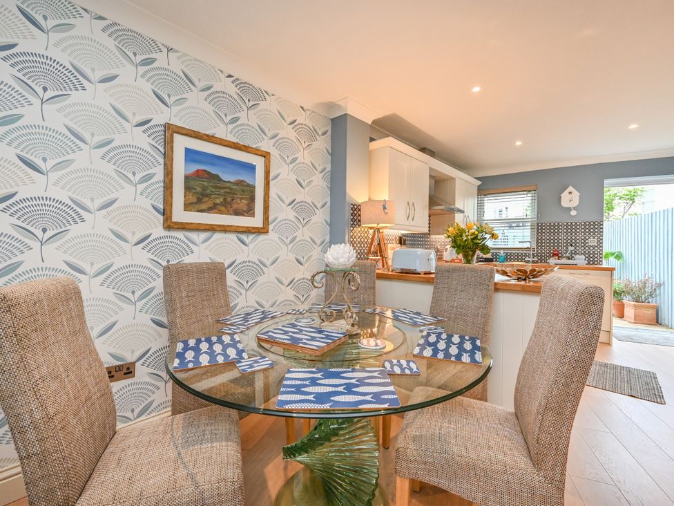 A dining room with a glass table and chairs at Lisburne Place in Torquay
