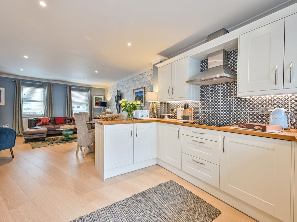 A kitchen with a living area in the background at Lisburne Place in Torquay