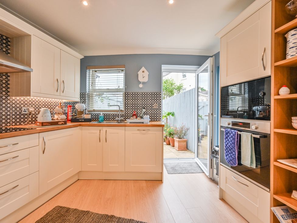 A kitchen with cabinets appliances and a door to the outdoor area at Lisburne Place in Torquay