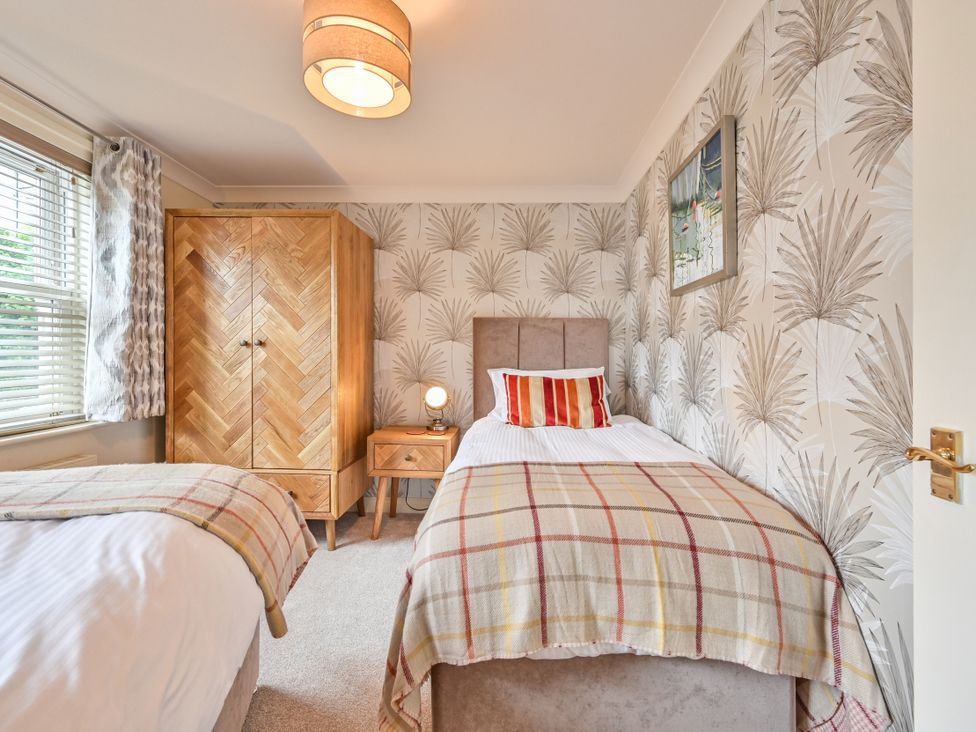 A bedroom with two beds and a wardrobe at Lisburne Place in Torquay