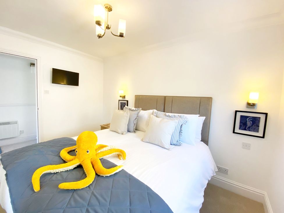 A bedroom with a bed, lamp, television and octopus plush toy at The Degas Sea View Suite in Torquay