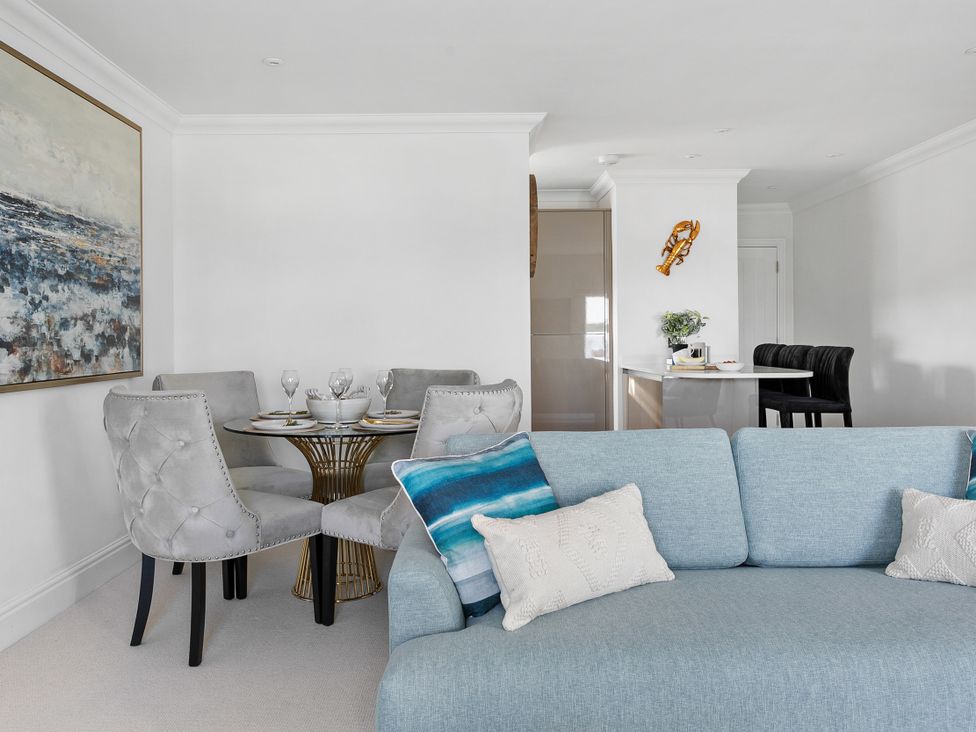 A living room with a dining area and sofa at The Renior Sea View Suite in Torquay