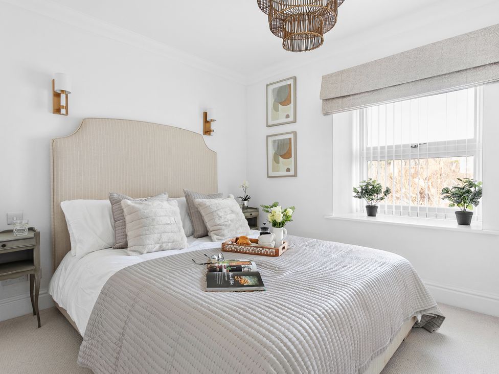 A bedroom with a bed, bedside table, and plants at The Renior Sea View Suite in Torquay