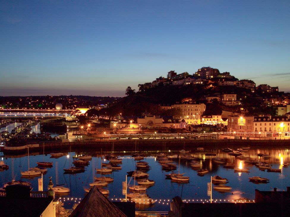 A view of boats on water with lights in background at The Renoir Sea View Suite in Torquay