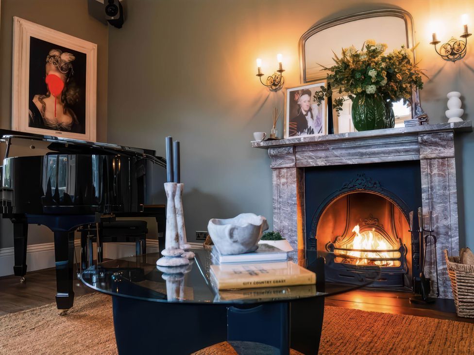 A living room with a fireplace and a piano at St Anne's Manor in Torquay