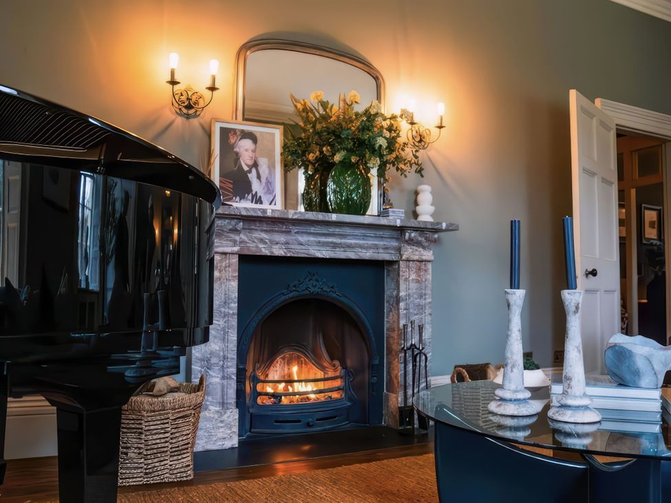 A living room featuring a piano, fireplace, and decorative items at St Anne's Manor in Torquay