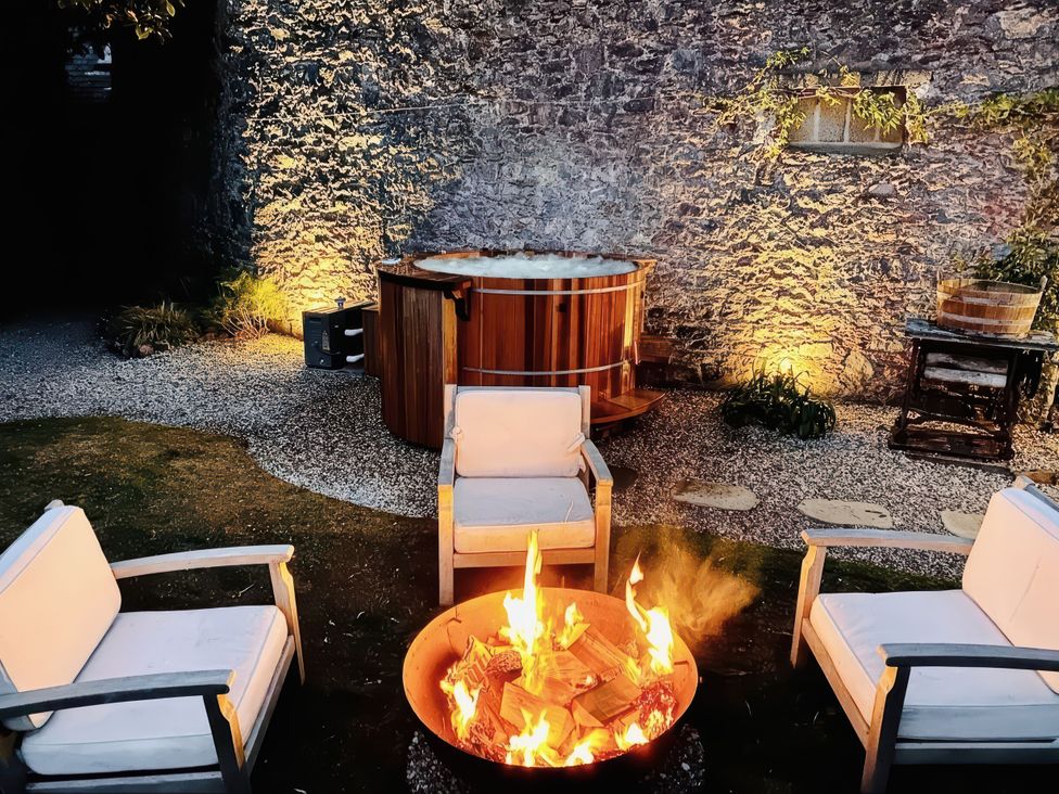 An outdoor seating area with a fire pit and hot tub at St Anne's Manor in Torquay