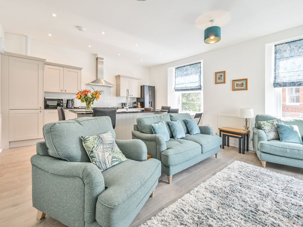 A living room with sofas and a kitchenette at The Falstone Apartment in Torquay
