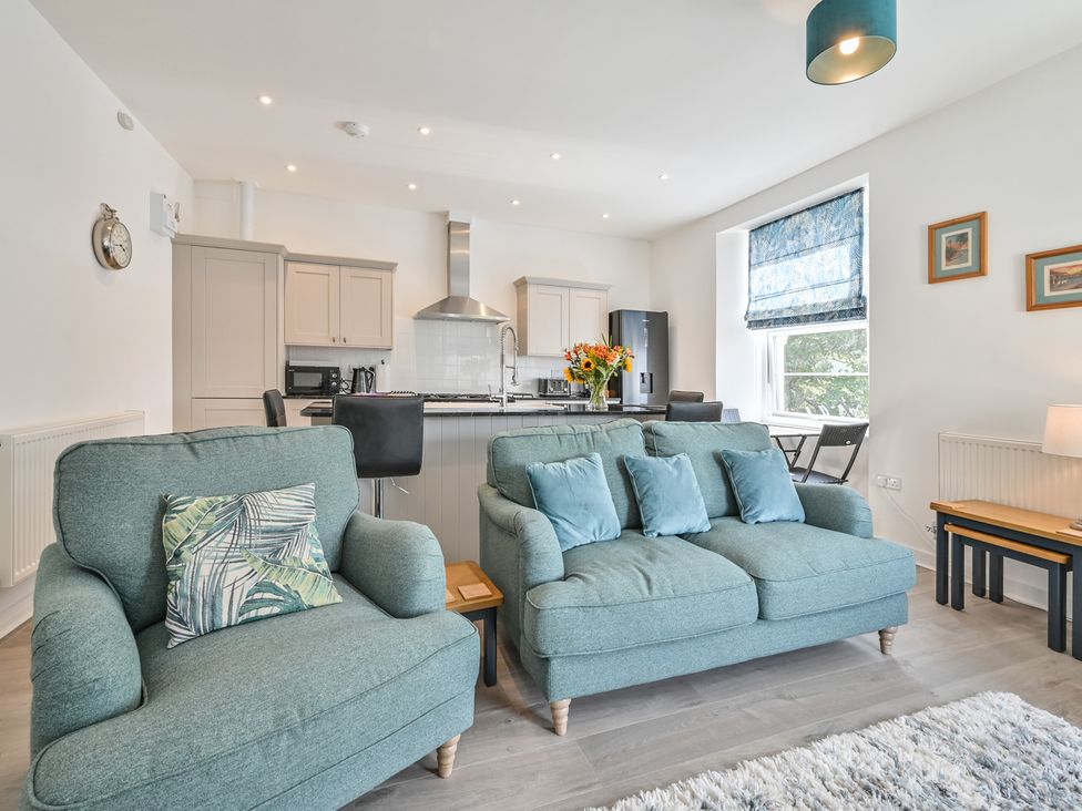 A living room with a sofa and kitchen area at The Falstone Apartment in Torquay