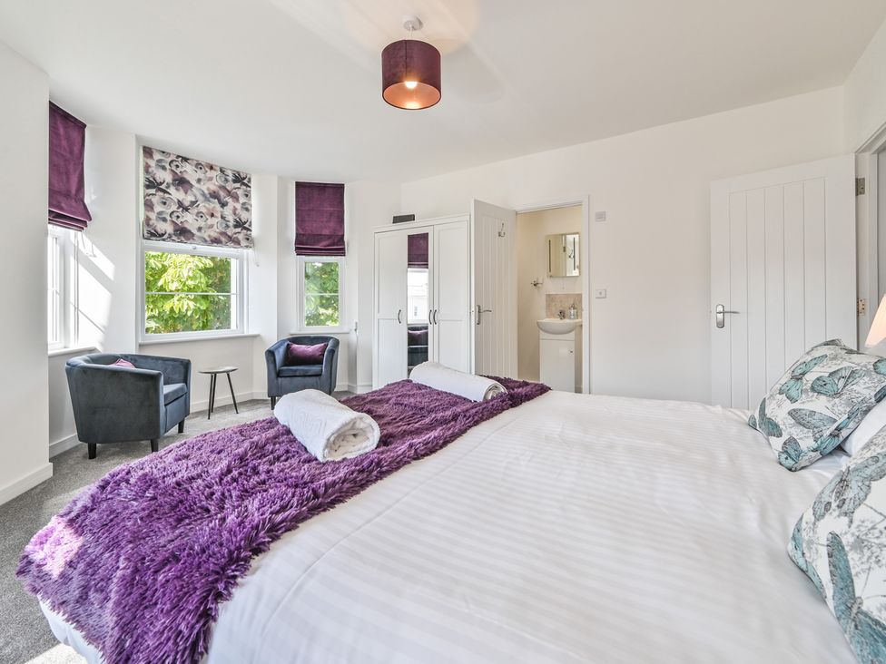 A bedroom with a bed, armchair, and bathroom access at The Falstone Apartment in Torquay