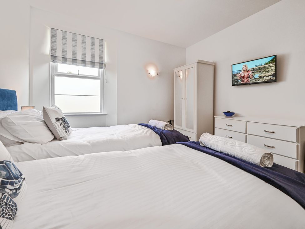 A bedroom with two beds and a television at The Falstone Apartment in Torquay