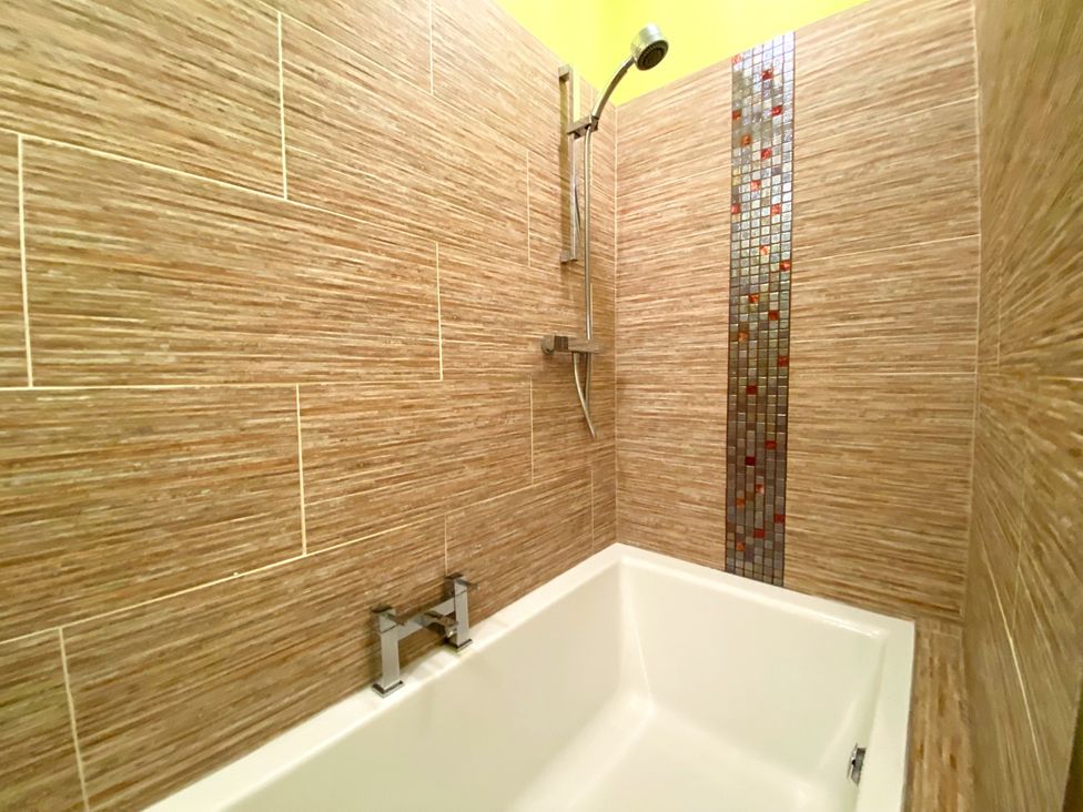 A bathroom with a bathtub and shower at Upper Stable - The Stables Apartments at Meadfoot Bay, Torquay